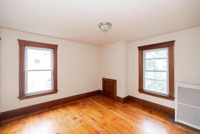 empty room with hardwood / wood-style flooring and radiator heating unit