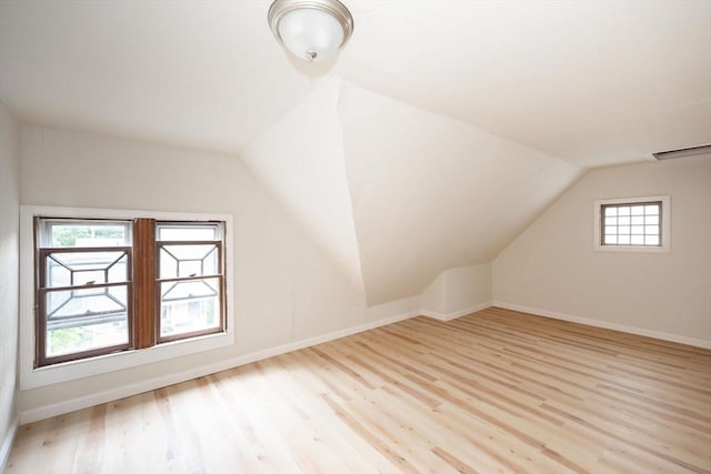 bonus room with light wood-type flooring and vaulted ceiling