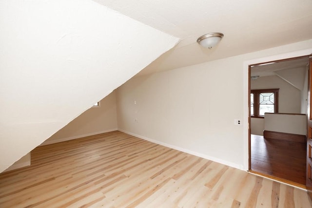 additional living space with light hardwood / wood-style flooring and lofted ceiling