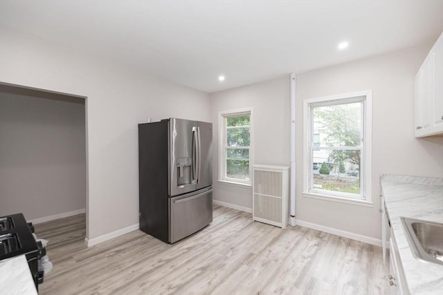 kitchen with black range with electric stovetop, white cabinetry, radiator heating unit, stainless steel fridge with ice dispenser, and light hardwood / wood-style flooring