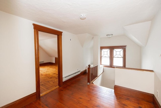 additional living space featuring lofted ceiling, dark wood-type flooring, and a baseboard radiator