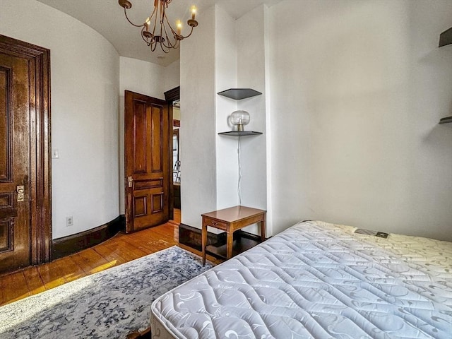 bedroom featuring wood-type flooring and an inviting chandelier