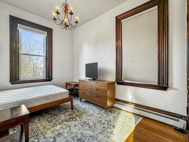 bedroom featuring hardwood / wood-style floors, an inviting chandelier, and a baseboard heating unit