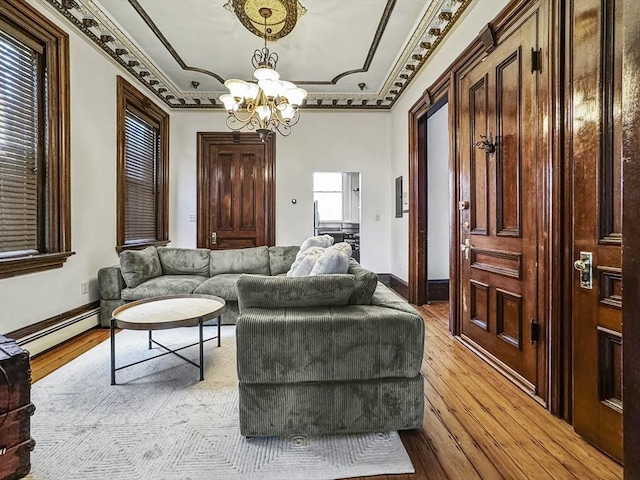 living room featuring a baseboard radiator, an inviting chandelier, light wood-type flooring, and crown molding