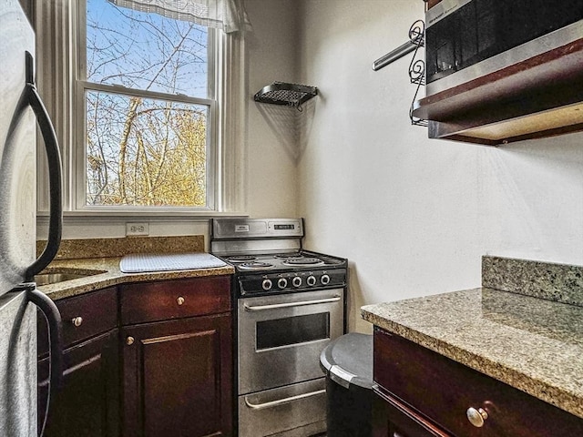 kitchen with fridge, plenty of natural light, dark brown cabinets, and stainless steel range with gas stovetop