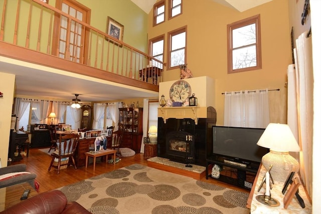 living room with ceiling fan, light hardwood / wood-style floors, and a high ceiling