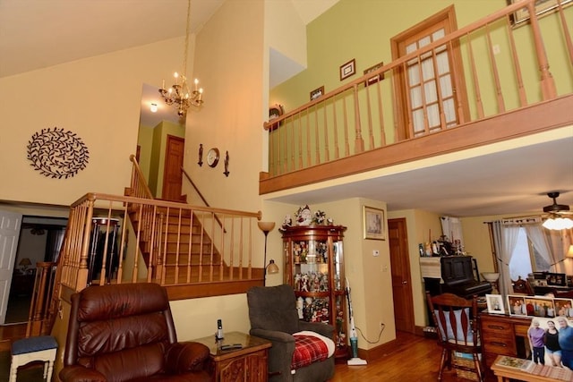 living room featuring a towering ceiling, dark wood-type flooring, and ceiling fan with notable chandelier