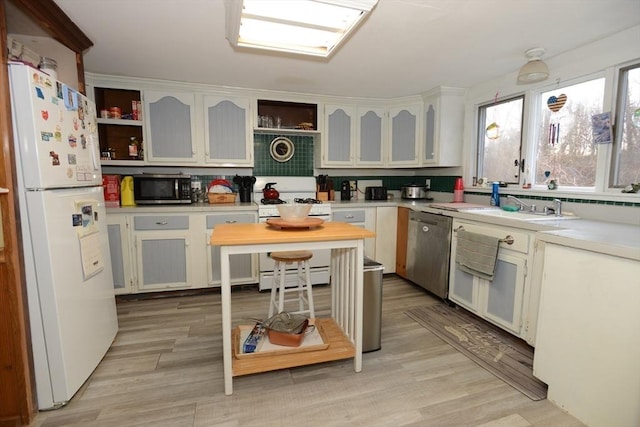 kitchen featuring stainless steel appliances, white cabinetry, light hardwood / wood-style floors, and sink