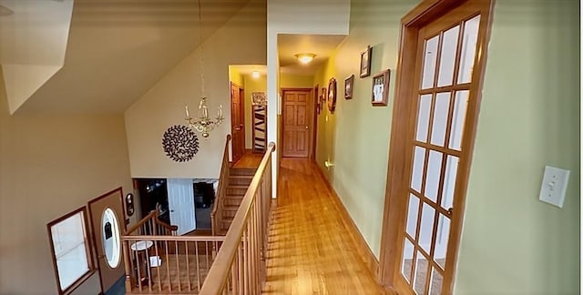 corridor with light wood-type flooring and an inviting chandelier