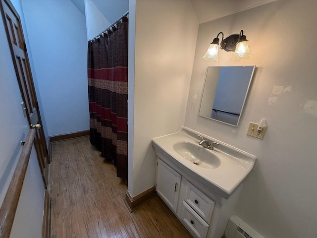 bathroom featuring wood-type flooring, vanity, a shower with curtain, and baseboard heating