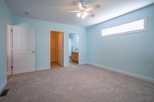 21 Cielo Dr, Dover, NH 03820 - unfurnished bedroom featuring a spacious closet, light colored carpet, a closet, a ceiling fan, and connected bathroom