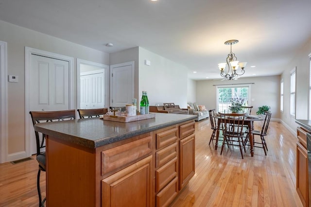 21 Cielo Dr, Dover, NH 03820 - kitchen featuring light wood-type flooring, a kitchen bar, dark countertops, a chandelier, and pendant lighting