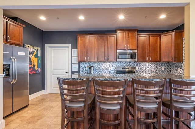 21 Cielo Dr, Dover, NH 03820 - kitchen with stainless steel appliances, dark stone countertops, tasteful backsplash, a kitchen bar, and recessed lighting