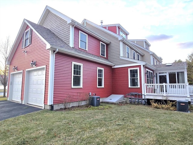 exterior space featuring a garage, a deck, cooling unit, and a lawn