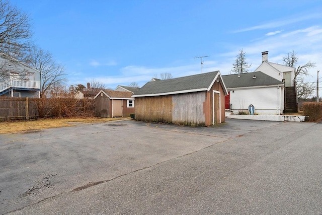 view of home's exterior with an outbuilding, a storage unit, and fence