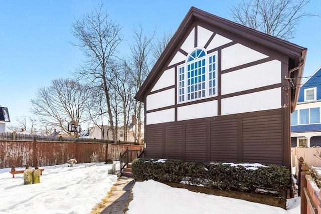 view of snowy exterior with fence and stucco siding