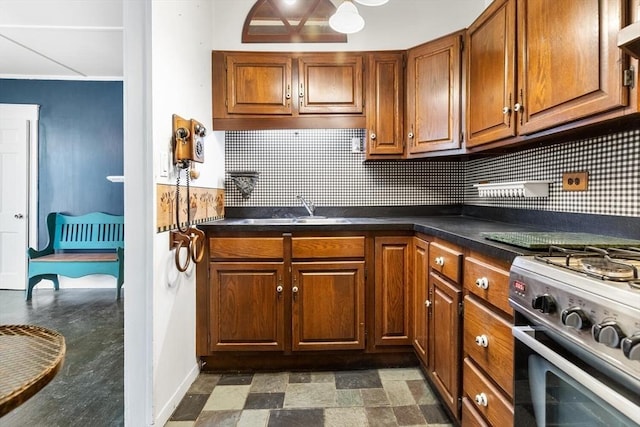 kitchen with dark countertops, brown cabinets, a sink, and backsplash