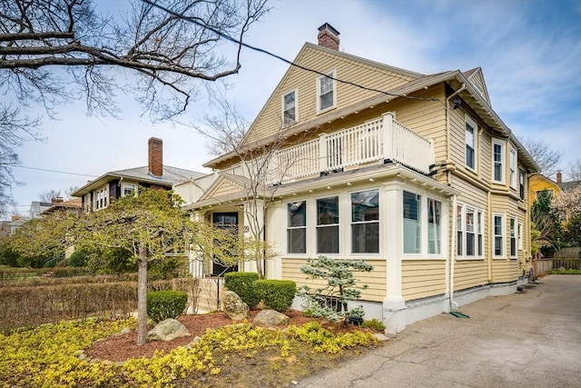 view of home's exterior with a chimney and a balcony