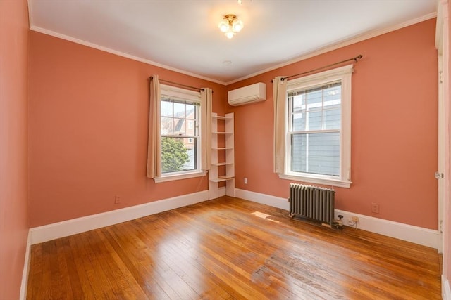 spare room with crown molding, baseboards, an AC wall unit, light wood finished floors, and radiator heating unit