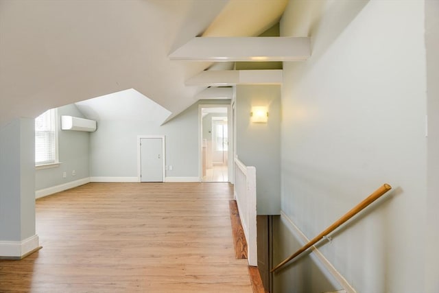 additional living space featuring plenty of natural light, a wall unit AC, and wood finished floors
