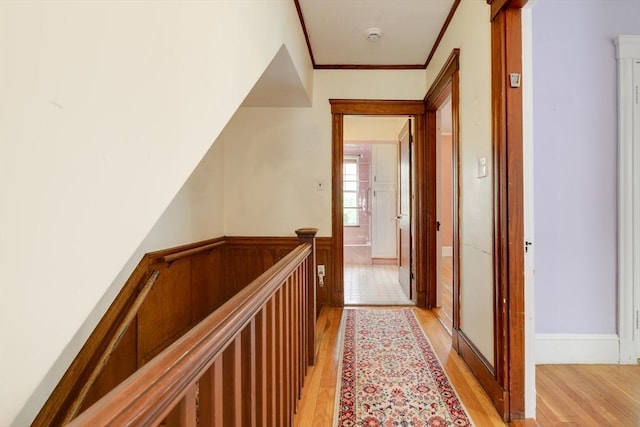 hallway with ornamental molding, light wood finished floors, and an upstairs landing