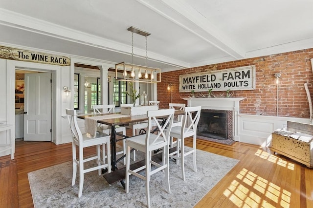 4 Porter St, Granby, MA 01033 - dining area with wood finished floors, beamed ceiling, a fireplace, brick wall, and a wainscoted wall