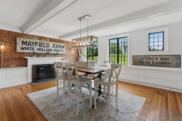 4 Porter St, Granby, MA 01033 - dining room featuring beam ceiling, a fireplace with flush hearth, wainscoting, brick wall, and a decorative wall