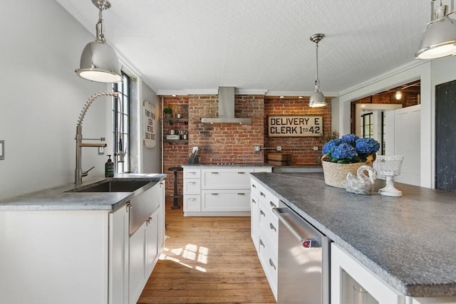 4 Porter St, Granby, MA 01033 - kitchen featuring wall chimney range hood, light wood-style flooring, brick wall, white cabinetry, and a sink