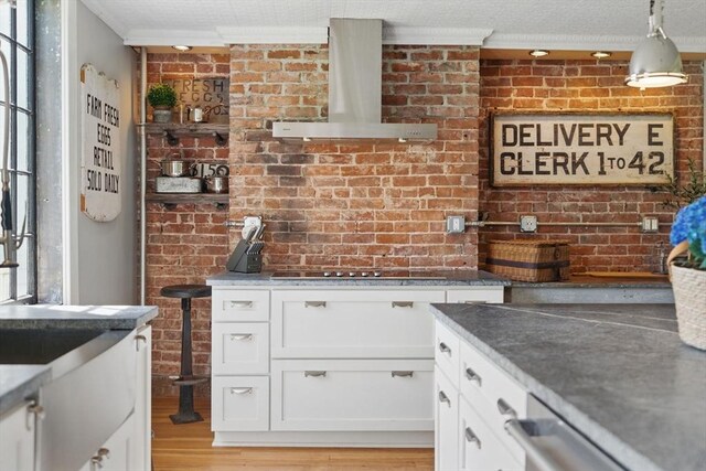 4 Porter St, Granby, MA 01033 - kitchen with exhaust hood, white cabinets, light wood finished floors, ornamental molding, and brick wall
