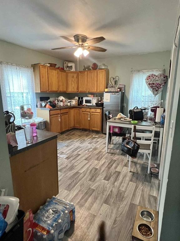 31 Abbott St, Lowell, MA 01852 - kitchen featuring freestanding refrigerator, dark countertops, a ceiling fan, light wood-style flooring, and brown cabinetry