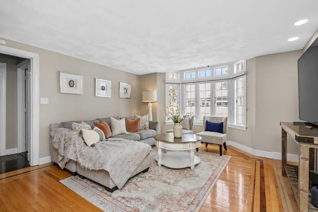 living area with light wood-type flooring, baseboards, and recessed lighting