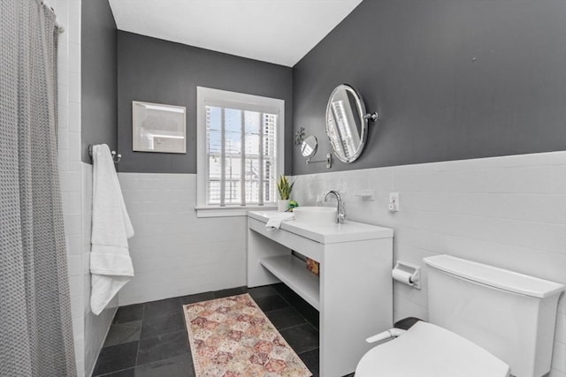 full bathroom featuring toilet, a wainscoted wall, vanity, tile walls, and tile patterned floors