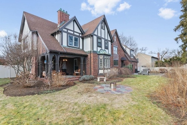 exterior space featuring a shingled roof, brick siding, stucco siding, a chimney, and a front yard