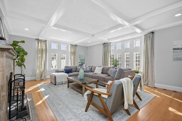 living room with a fireplace with raised hearth, light wood-type flooring, coffered ceiling, and baseboards