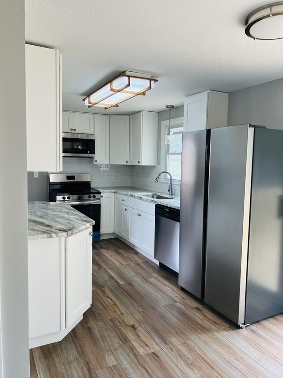 209 Casey Dr, Chicopee, MA 01020 - kitchen with appliances with stainless steel finishes, wood finished floors, light stone counters, and white cabinets