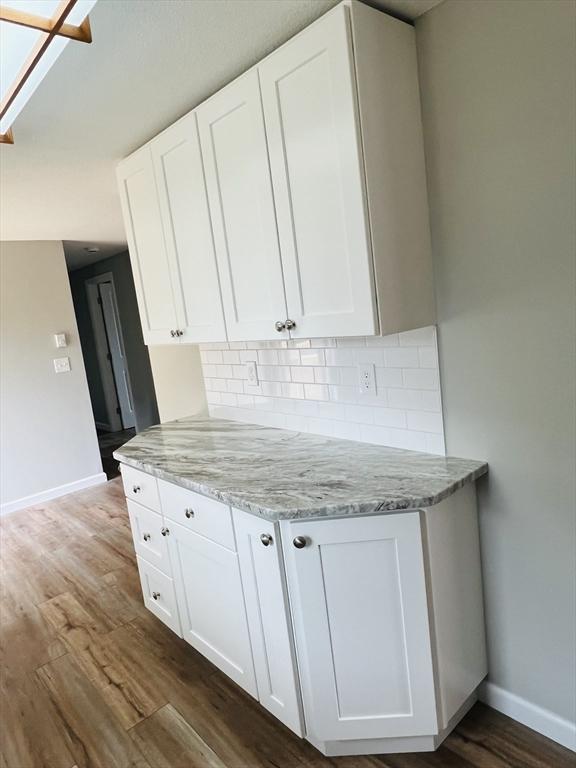 209 Casey Dr, Chicopee, MA 01020 - kitchen featuring dark wood-style floors, white cabinets, decorative backsplash, and light stone countertops