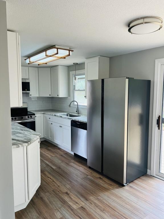 209 Casey Dr, Chicopee, MA 01020 - kitchen with stainless steel appliances, white cabinets, dark wood finished floors, decorative backsplash, and a textured ceiling