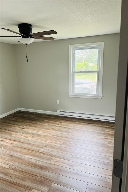 209 Casey Dr, Chicopee, MA 01020 - empty room featuring a baseboard heating unit, ceiling fan, and light wood-type flooring