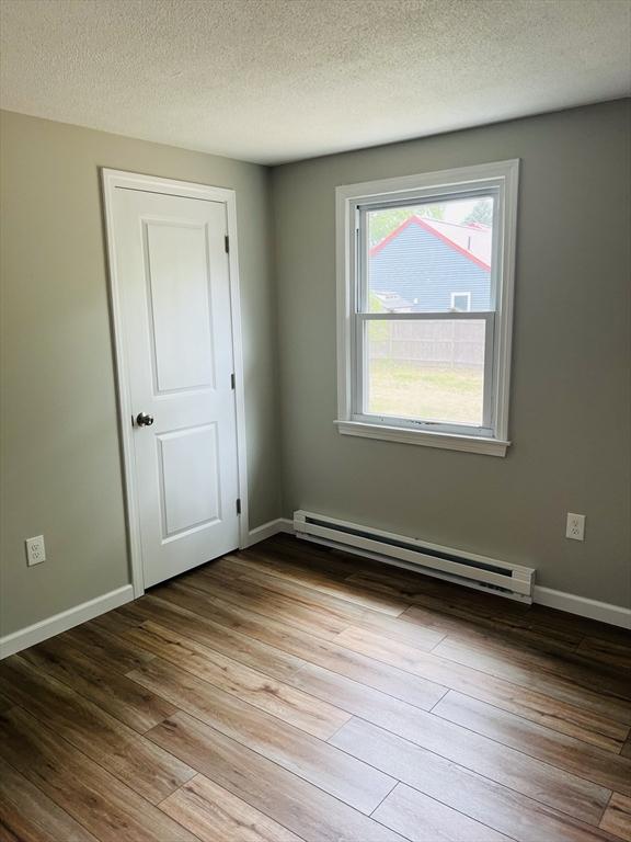 209 Casey Dr, Chicopee, MA 01020 - spare room featuring baseboard heating, wood finished floors, and a textured ceiling