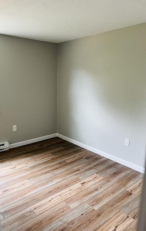 209 Casey Dr, Chicopee, MA 01020 - empty room with wood finished floors, a baseboard heating unit, and a textured ceiling