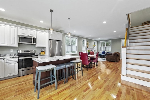 10 Stone St Unit 1, Auburn, MA 01501 - kitchen featuring ornamental molding, light wood-style flooring, white cabinets, a kitchen bar, and appliances with stainless steel finishes