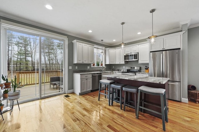 10 Stone St Unit 1, Auburn, MA 01501 - kitchen with ornamental molding, a kitchen island, appliances with stainless steel finishes, light wood finished floors, and hanging light fixtures