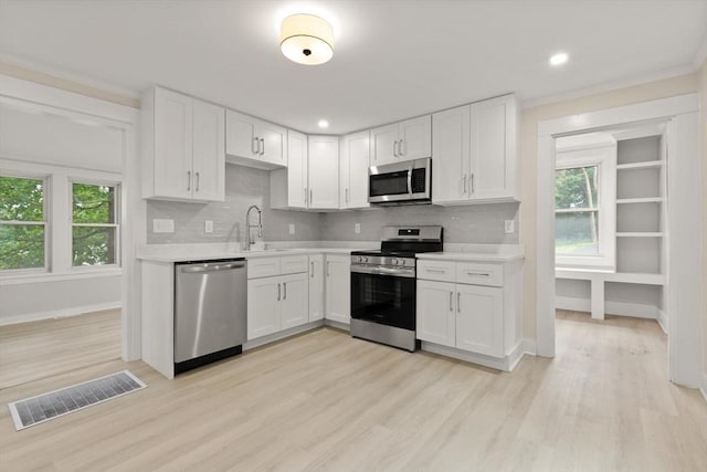 25 Norfolk St, Canton, MA 02021 - kitchen with stainless steel appliances, light countertops, light wood-style flooring, white cabinets, and ornamental molding