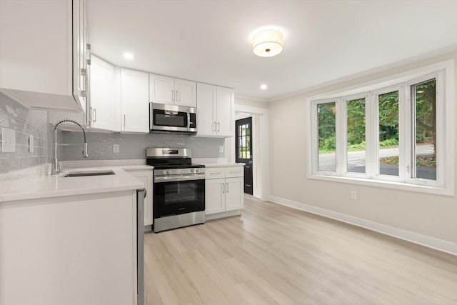 25 Norfolk St, Canton, MA 02021 - kitchen with stainless steel appliances, light countertops, white cabinetry, decorative backsplash, and light wood-style flooring