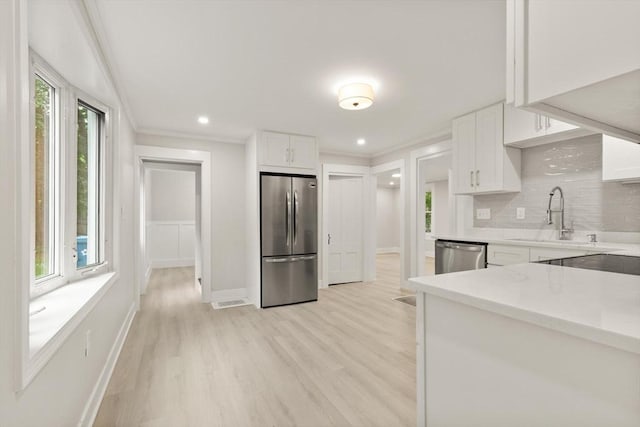 25 Norfolk St, Canton, MA 02021 - kitchen featuring stainless steel appliances, healthy amount of natural light, light wood-style flooring, white cabinets, and crown molding