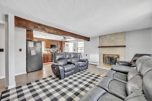 14 Greenville St, Billerica, MA 01821 - living area featuring a ceiling fan, a textured ceiling, a fireplace, a baseboard radiator, and light wood-style flooring