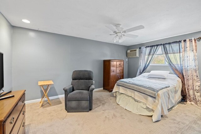 bedroom with an AC wall unit, baseboards, light colored carpet, and a ceiling fan