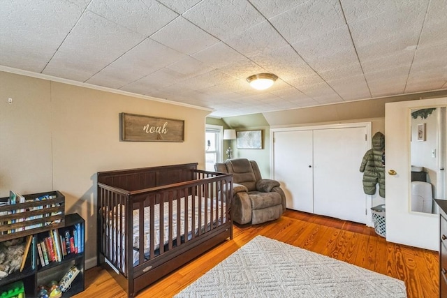 bedroom featuring crown molding, wood-type flooring, and a closet