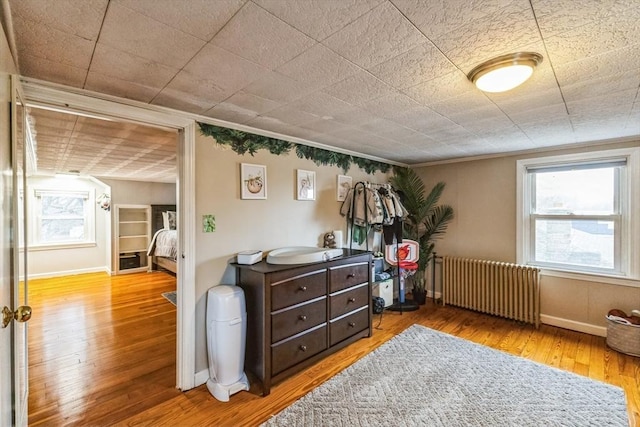 interior space with hardwood / wood-style floors, radiator heating unit, and ornamental molding