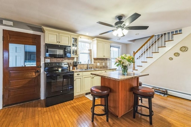 kitchen with sink, black appliances, and cream cabinetry